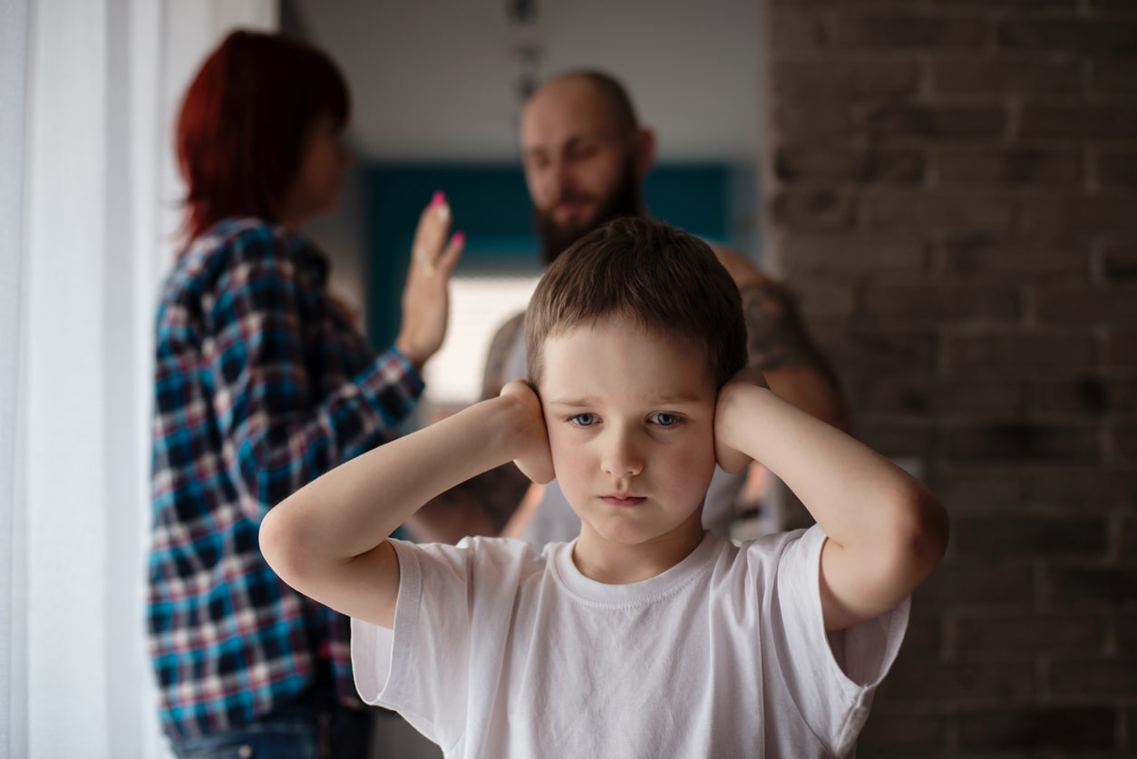 boy covering his ears as couple fights