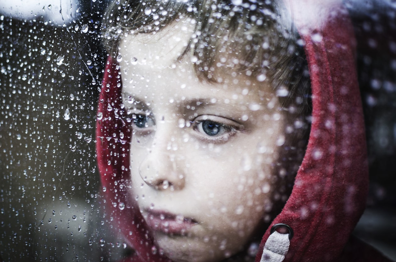 Traumatized little boy looking out window