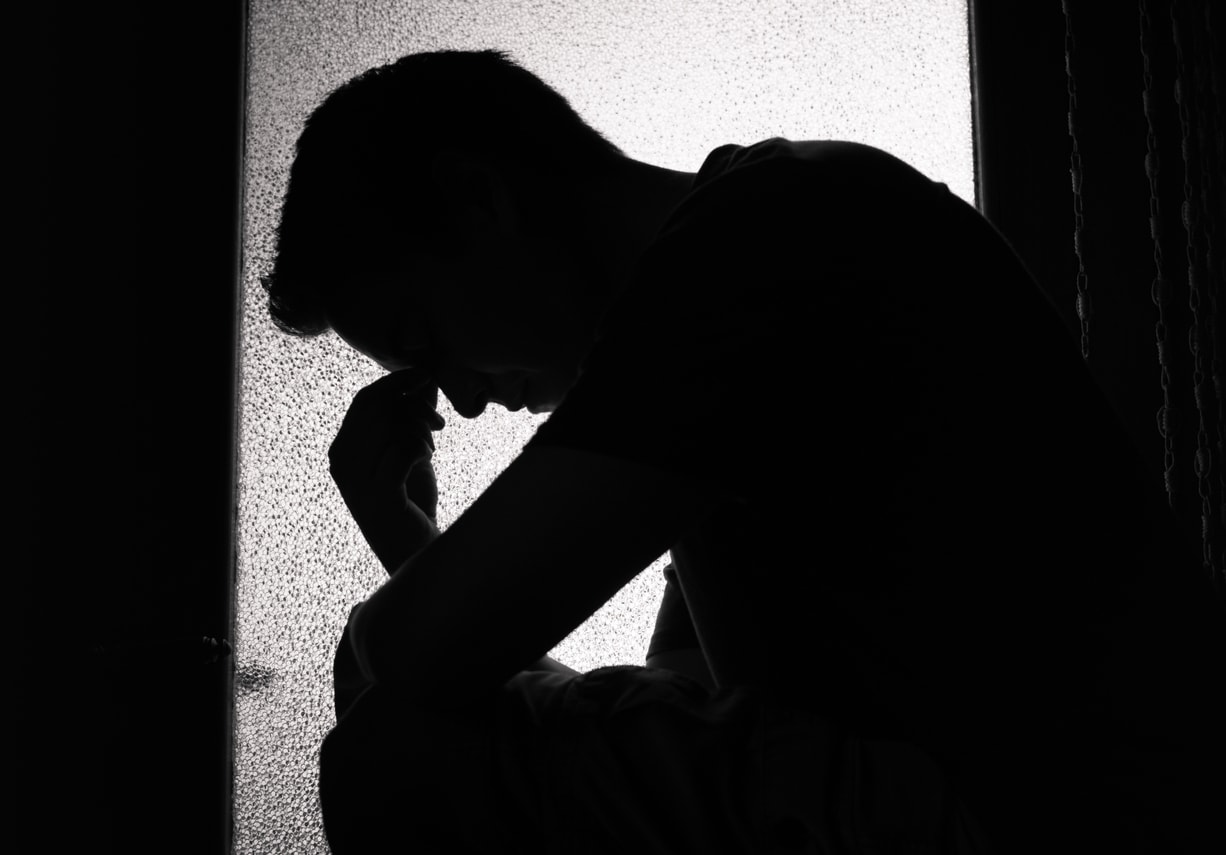 Depressed man sitting in window